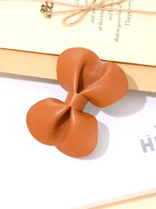 Detailweergave van de getextureerde bruine lederen strik van deze elegante haarklem.