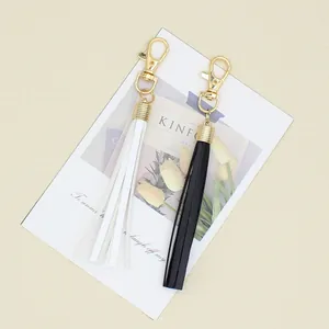 Close-up detail of black and white leather tassel keychains with golden alloy lobster clasps