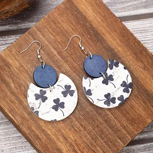 Detailed view of crescent leather and wood earrings with dark blue shamrock pattern print