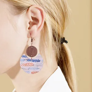 Detail shot of bohemian crescent leather and wood drop earrings on a female model
