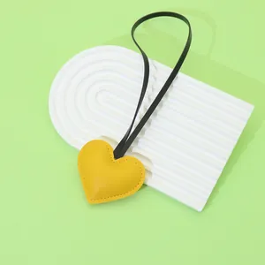 Close-up of yellow leather heart-shaped bag charm on a decorative white tray