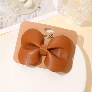 Elegante bruine leren strik haarclip gepresenteerd op een minimalistische kaart