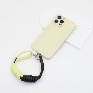 Detalle de una correa de muñeca para móvil en cuero PU trenzado de color amarillo y negro.