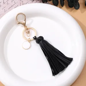 Elegante llavero de borla de cuero negro con cierre de langosta dorado en plato blanco