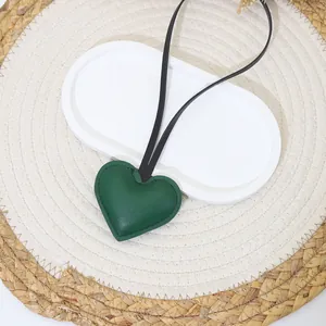 Close-up detail of dark green leather heart-shaped bag charm with fine stitching