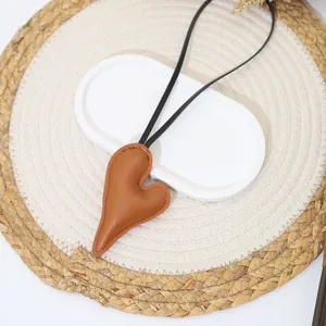 Close-up detail of a brown heart-shaped leather bag charm on a natural woven placemat