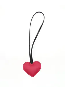 Detailed close-up of a red leather heart-shaped pendant with minimalist black strap