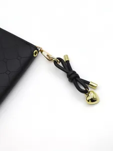 Detailed view of black leather bow charm and gold heart pendant on zipper pull
