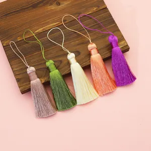 Detail shot of five colorful polyester tassels arranged on a wooden board for DIY projects.