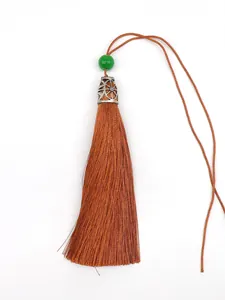 Close-up detail of a silky brown polyester tassel with a green bead and silver metal cap
