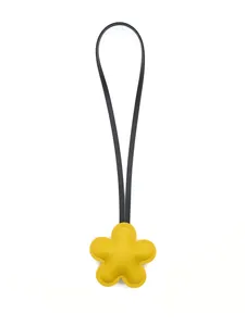 Close-up of a cute yellow flower leather bag charm with a long black strap.
