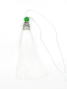 Detailed view of white polyester vertical tassel with green bead and silver crown cap