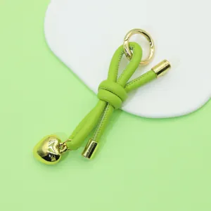 Detail view of light green knotted leather keychain featuring a polished gold heart charm