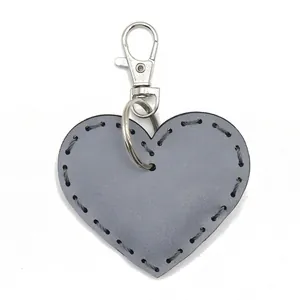 Portachiavi in pelle riflettente a forma di cuore con dettagli cuciti a mano e moschettone.