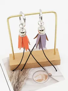 Detail view of handmade PU leather tulip tassel charms in orange and purple on a stand.