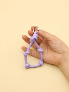 A hand holding a purple knotted leather keychain lanyard with a silver metal ring