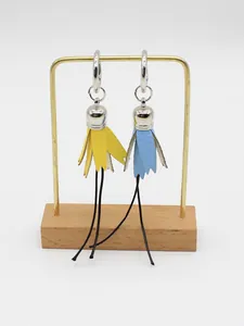 Macro view of handmade yellow and blue PU ball tassel charms on a metal display stand
