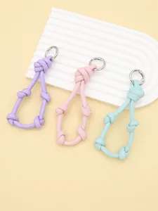Detailed view of three pastel woven leather knotted keychains with silver metal rings