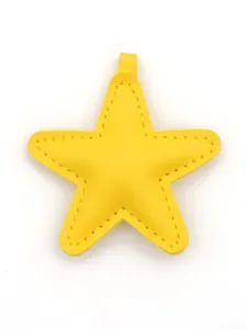 Detailed view of a yellow leather star-shaped bag charm with fine decorative stitching