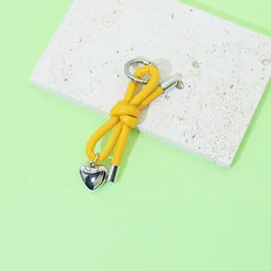 Detailed view of the knotted yellow leather keychain with a silver heart pendant.