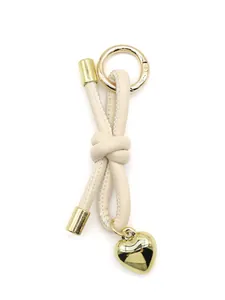 Elegant beige leather knotted cord keychain featuring a polished gold-tone heart charm