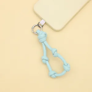 Detail shot of light blue leather knotted phone strap lanyard on yellow background