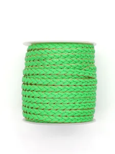 Detailed view of bright green braided PU leather cord with gold trim on white spool