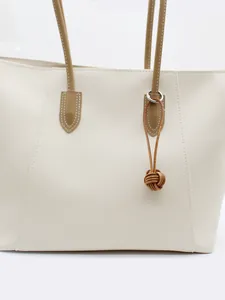 Macro detail view of a brown handmade leather monkey fist knot keychain on white bag