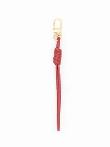 Detail view of a red hand-braided PU leather keychain with a gold lobster clasp.