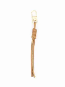 Detailed close-up view of a handmade braided PU leather keychain in tan with gold clasp