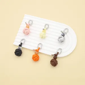 Close-up view of six colorful handmade woven PU leather ball-shaped charms on a white stand