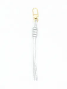 Macro view of silver hand-woven PU leather cord keychain with elegant gold-toned clasp.