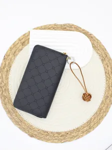 Detailed view of handmade leather monkey's fist knot keychain on black embossed wallet