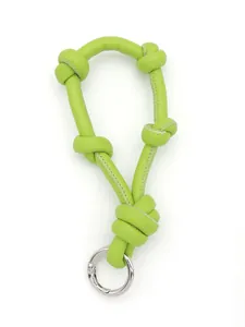 Close-up of vibrant lime green knotted leather strap bag charm with silver metallic ring