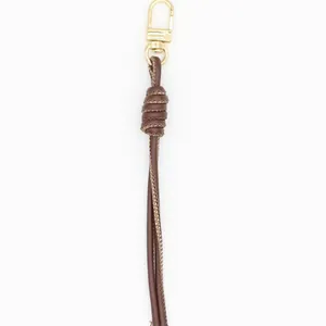Macro detail view of a brown PU leather braided keychain with a gold metal clasp