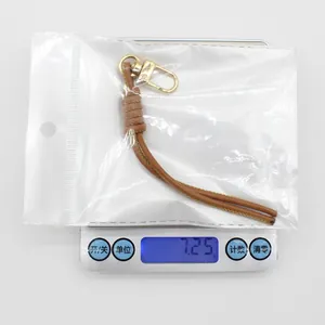 Close-up detail of a brown PU leather braided keychain weighing 7.25 grams on a scale