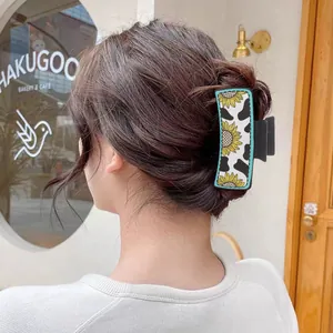 Detailaufnahme einer Haarklammer mit Kuhmuster und Sonnenblumen im Western-Stil am Dutt