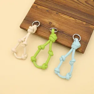 Three colorful braided leather knot keychains in beige, green, and blue with silver rings.
