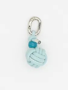 Macro detail of a light blue handwoven PU sphere bag charm with silver metallic clip