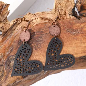 Detailed close-up showing the hollow mesh pattern of heart earrings with a wood piece