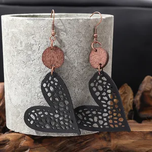 Macro view of unique heart-shaped hollow leather earrings with rustic wooden discs.