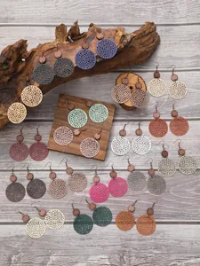 Collection de boucles d'oreilles rétro en cuir ajouré et bois sur fond de bois.