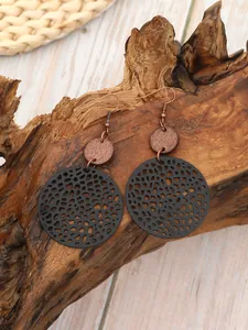 Détail des boucles d'oreilles vintage en cuir évidé et perles de bois naturel