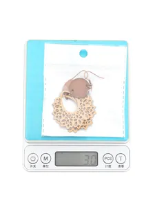 Macro view of bohemian hollow wood earrings on a digital scale weighing 3.0 grams