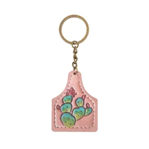 Close-up of a pink faux leather cow tag keychain featuring an embossed green cactus illustration