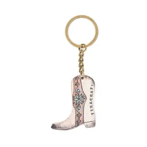 Detalle de un colgante de bota de vaquero vintage en un llavero de bronce de estilo rústico