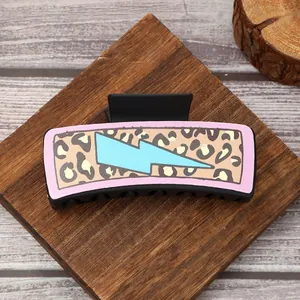 Detail of a Western style hair claw clip with leopard print and blue lightning bolt design.