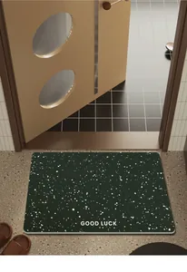 Dettaglio del tappetino da bagno in diatomite verde scuro con puntini bianchi e Good Luck.
