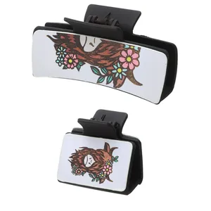 Detail view of two black hair claws with highland cow and floral leather inserts