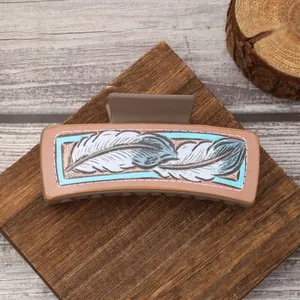 Close-up of Western style hair claw clip featuring a blue and white feather pattern